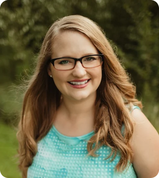 A blonde woman with glasses, smiling.